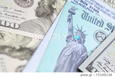 United States IRS Stimulus Check with Statue of Liberty Wearing Medical Face Mask Resting on Money United States IRS Stimulus Check with Statue of Liberty Wearing Medical Face Mask Resting on Money 73100136