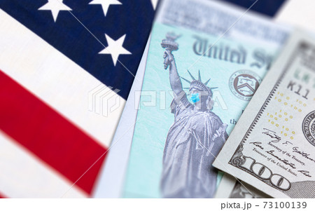 United States IRS Stimulus Check with Statue of Liberty Wearing Medical Face Mask Resting on American Flag 73100139