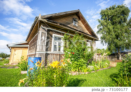 Typical rural wooden house in russian village with decorative flowers 73100177