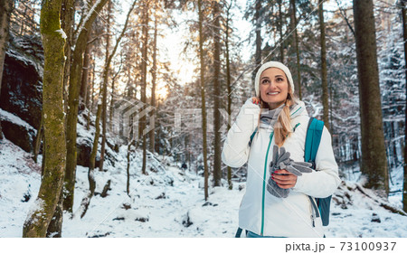 Woman on winter hike enjoying the sunset in the forest Woman on winter hike enjoying the sunset in the forest 73100937
