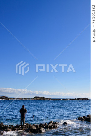 海辺で釣りをする男性の後ろ姿の写真素材