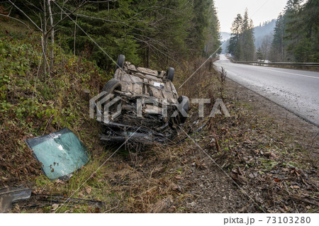 The Car Got Into an Accident on the Mountain Road and fell Upside Down. The Blue Car Turned over in a Ditch near the Highway 73103280