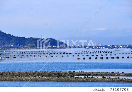 万石浦の干潟、養殖ブイ、万石橋と石巻市渡波の街並み 73107708