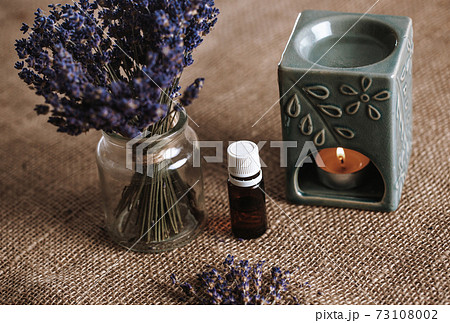 Aroma lamp with an aromatic oil and burning candle with bucket of lavender in the glass, aromatherapy concept 73108002