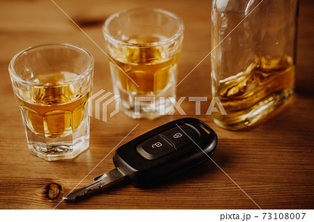 Close up of car keys and an alcohol on the table, alcoholism 73108007