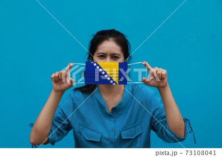 A woman and hygienic mask with Bosnia and Herzegovina flag pattern in her hand A woman and hygienic mask with Bosnia and Herzegovina flag pattern in her hand 73108041