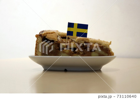 Apple cake triangular cut from big round cake with Sweden toothpick flag 73110640