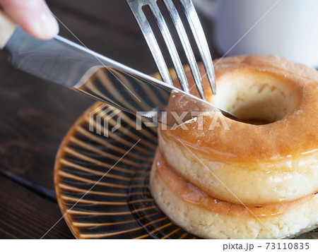 フォークとナイフで食べる、蜂蜜がたっぷりかかったドーナツ型のスコーン。 フォークとナイフで食べる、蜂蜜がたっぷりかかったドーナツ型のスコーン。 73110835