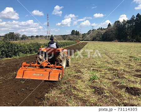 トラクターで耕うんする男性 73114305