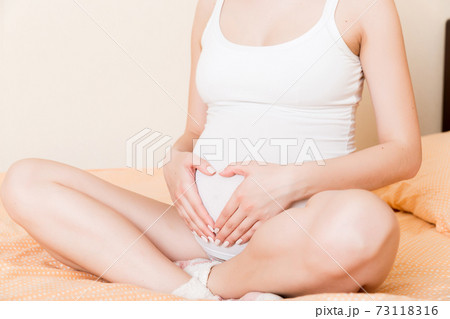 happy pregnant woman making heart in home on bed. Pregnancy, love and expectation concept 73118316