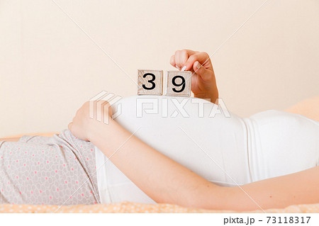 Pregnant woman in white underwear on bed in home holding calendar with weeks 39 of pregnant. Maternity concept. Expecting an upcoming baby 73118317