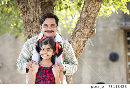 Rural Indian father with daughter looking at camera Rural Indian father with daughter looking at camera 73118428