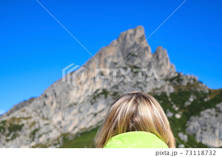 A girl looks at the Dolomites in Italy. Back view. Out of focus. 73118732