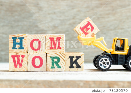Bulldozer hold letter block E to complete word homework on wood background Bulldozer hold letter block E to complete word homework on wood background 73120570