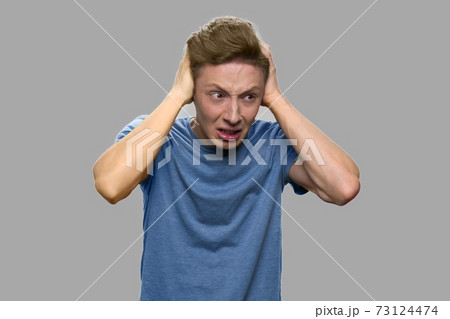 Crazy teen guy holding hands on head. Crazy teen guy holding hands on head. 73124474