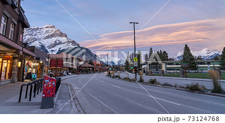 Street view of Banff Avenue in autumn evening. Snow capped Cascade Mountain with pink rosy sky in the background. Alberta, Canada. 73124768