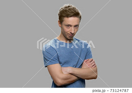 Teen boy looking aggressive against gray background. 73124787