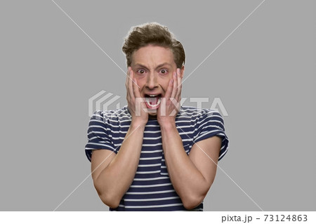 Shocked scared teen boy is screaming on gray background. 73124863
