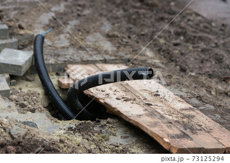 Thin diameter ribbed black PVC pipe in the ground before laying 73125294