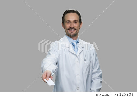 Successful male doctor offering business card. Successful male doctor offering business card. 73125303