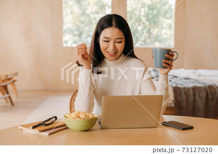 Young teenage Asian woman wears sweater with pretty smile in bed room. Happy smiling girl using laptop with notebook watching movies, films, videos online. .Online technology concept. 73127020