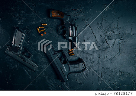 Three guns and bullets on black table. 73128177