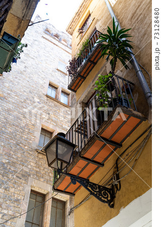 Yellow historic house with street light, flowers and balconies in Barcelona Yellow historic house with street light, flowers and balconies in Barcelona 73128480