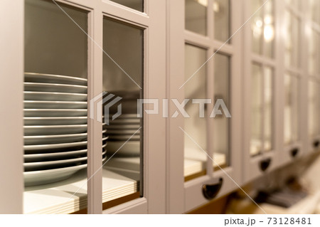Row of plates in gray wooden cabinet with glass windows in traditional style Row of plates in gray wooden cabinet with glass windows in traditional style 73128481