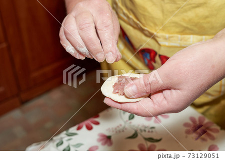 Hands hold a piece of raw dough and minced meat Hands hold a piece of raw dough and minced meat 73129051