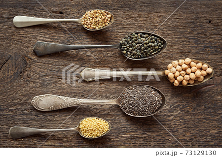 Seeds and legumes - millet, chia, chickpeas, lentils and buckwheat on five vintage spoons, top view 73129130
