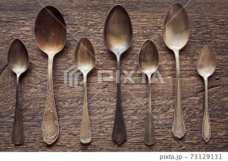 Seven empty alpacca vintage spoons on a wooden background, top view 73129131