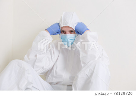 A sad doctor sits on the floor in the corridor of the hospital. Health workers during the Covid19 coronavirus pandemic 73129720