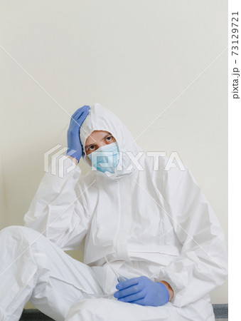 A sad doctor sits on the floor in the corridor of the hospital. Health workers during the Covid19 coronavirus pandemic A sad doctor sits on the floor in the corridor of the hospital. Health workers during the Covid19 coronavirus pandemic 73129721