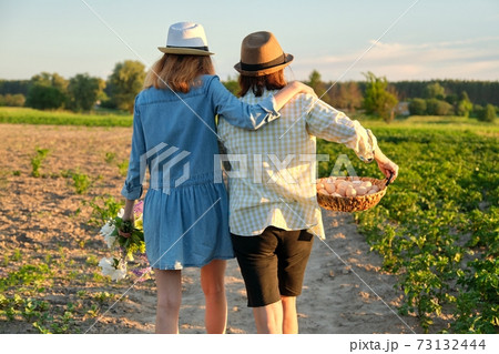 Women mother and daughter with basket of eggs, lifestyle, nature, garden, back view 73132444