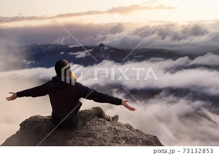 Adventurous Man with Open Hands is taking in the momen on top of a mountain. Adventurous Man with Open Hands is taking in the momen on top of a mountain. 73132853