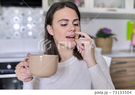 Young beautiful woman taking pill vitamin a, d, e, fish oil, omega-3 Young beautiful woman taking pill vitamin a, d, e, fish oil, omega-3 73133504