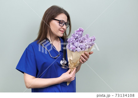 Doctor's Day, celebration. Happy smiling female medic with bouquet of flowers 73134108