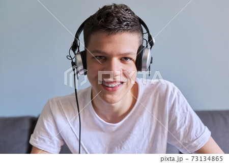 Portrait of student boy teenager in headphones looking at webcam, videocall 73134865