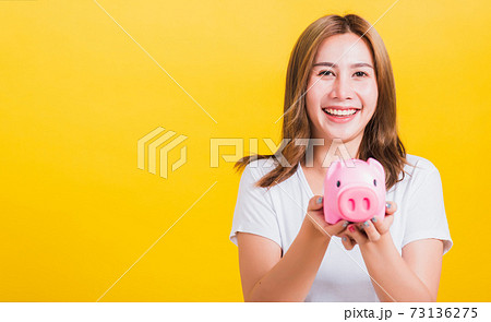 woman smiling hold piggy bank with a lots money woman smiling hold piggy bank with a lots money 73136275