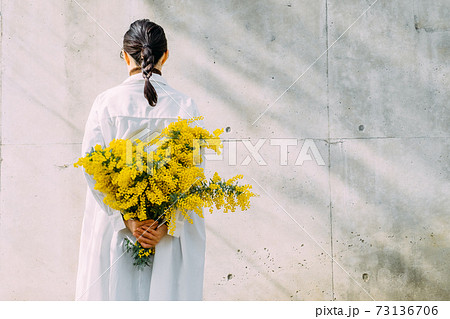 ミモザの花束を持つ女性の写真素材