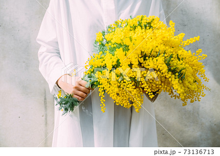 ミモザの花束を持つ女性の写真素材