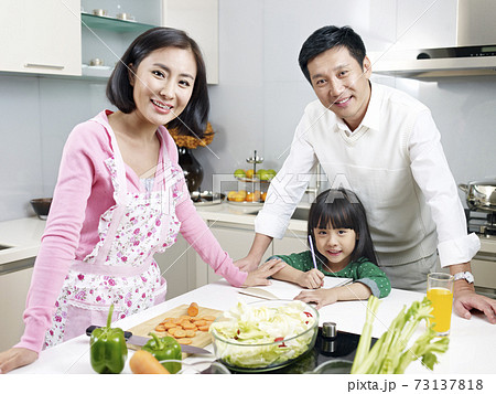 portrait of an asian family of three smiling in kitchen 73137818