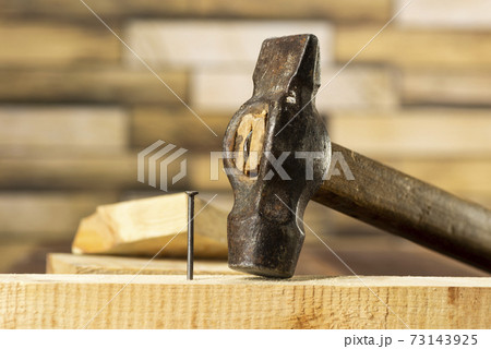 Hammer a nail into a wooden board, work, carpentry, close up hammering a nail 73143925