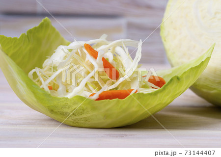 Fresh white cabbage and fresh cabbage salad with carrots with original serving on a cabbage leaf 73144407