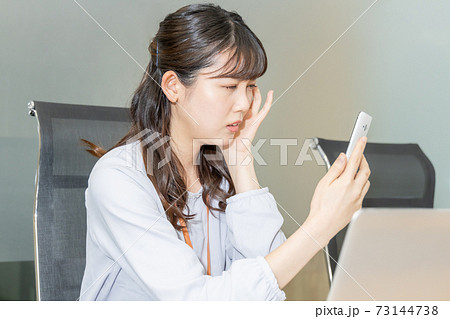 スマホ画面を見て悩む女性 スマホ画面を見て悩む女性 73144738