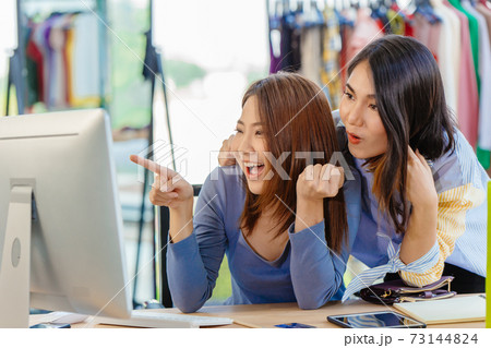Asian woman with friend exciting hand pointing at computer screen for happy young SME business owner concept. 73144824
