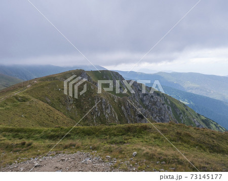 View from grassy hill slopes of hiking trail from Chopok at mountain meadow ridge Low Tatras mountains, Slovakia. Fog and clouds, late summer day View from grassy hill slopes of hiking trail from Chopok at mountain meadow ridge Low Tatras mountains, Slovakia. Fog and clouds, late summer day 73145177