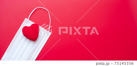 heart shape decoration and Medical face mask on red background against Coronavirus disease infection. Love, together and Happy Valentines day under Covid-19 pandemic concept heart shape decoration and Medical face mask on red background against Coronavirus disease infection. Love, together and Happy Valentines day under Covid-19 pandemic concept 73145356