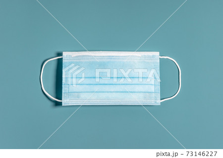Surgical mask with rubber ear straps on blue background. Surgical mask with rubber ear straps on blue background. 73146227