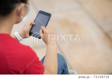 Asian woman sit on skateboard using smartphone in modern city 73148719